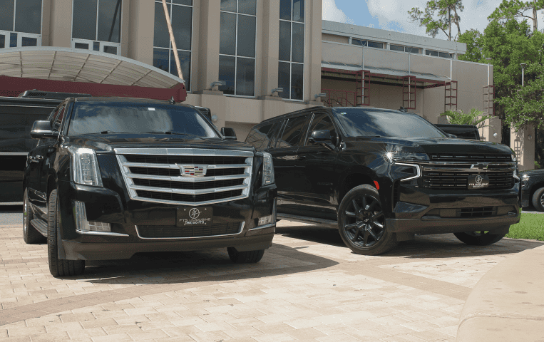 FTS Limousine & Black Car SUV's. New Model SUV's - A Black Cadillac Escalade and Chevrolet Suburban parked at the UF Center for Performing Arts.