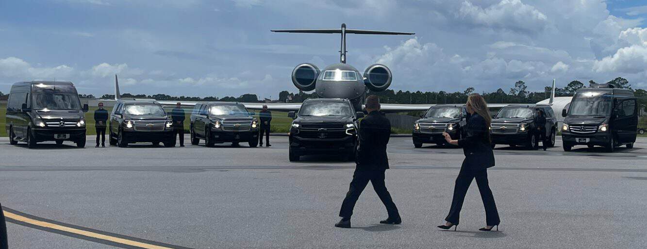FTS Limousine leadership team directs a lineup of executive vans, SUVs, and private airport transportation vehicles positioned in front of a private jet.