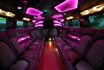 Upscale limousine interior with leather seating, mood lighting, and luxury amenities.