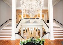 Interior of the Blanche Hotel in Lake City Florida featuring a grand staircase and large chandelier.