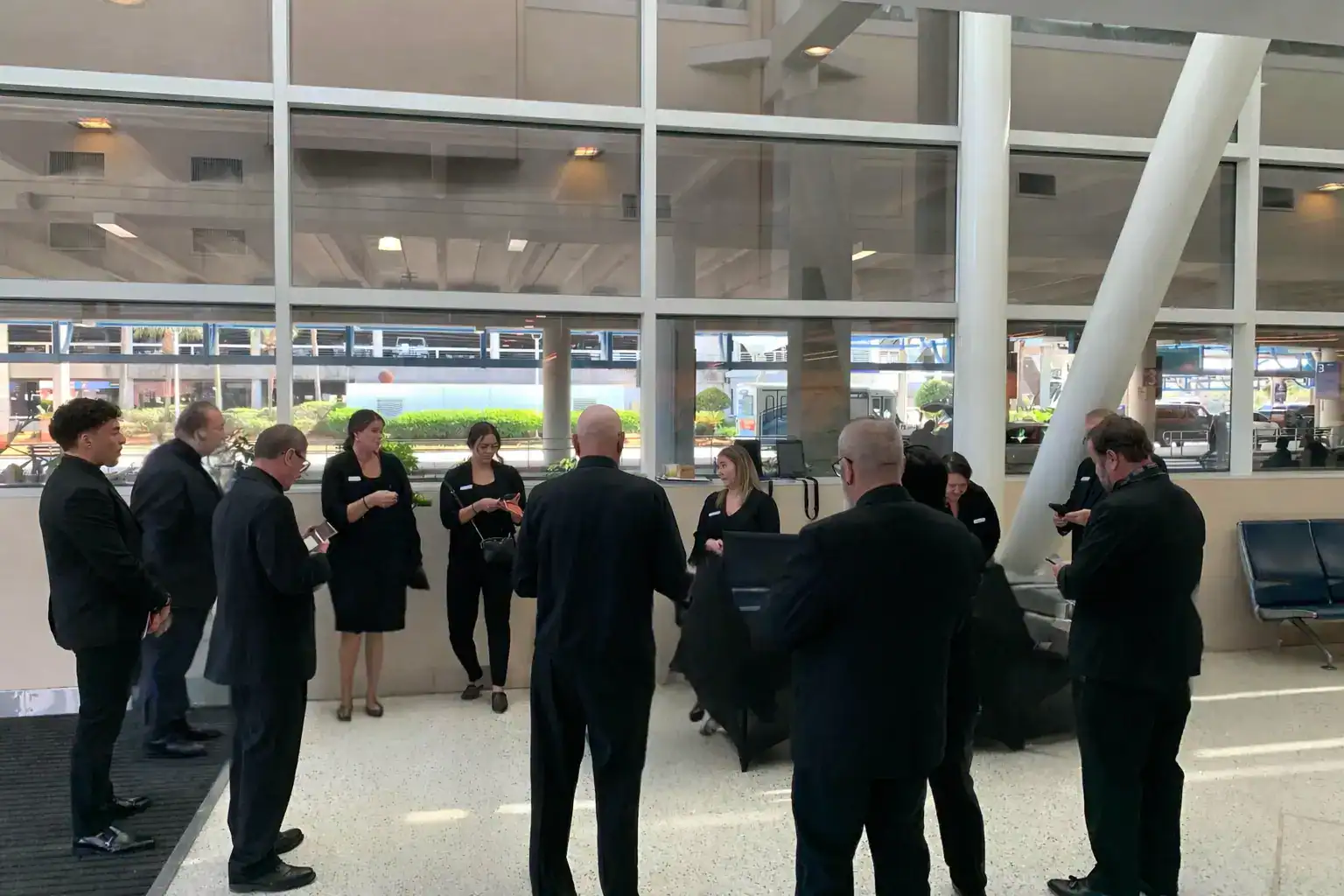 Operations manager briefing FTS chauffeurs and event staff inside Jacksonville International Airport before coordinating VIP airport arrivals.