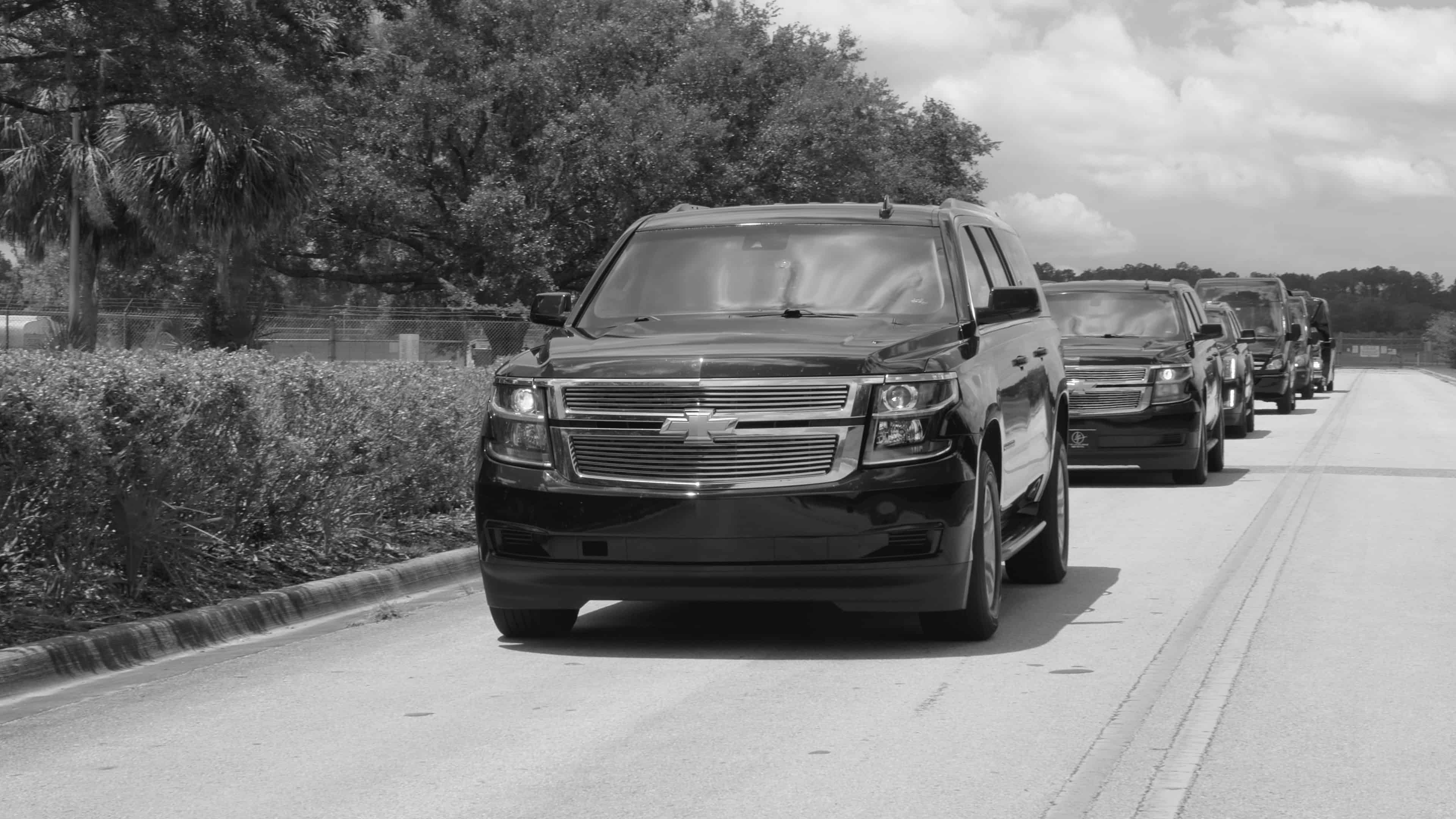 Luxury SUVs, executive vans, and shuttle vehicles traveling together in a coordinated motorcade providing executive transportation in Gainesville, Florida.