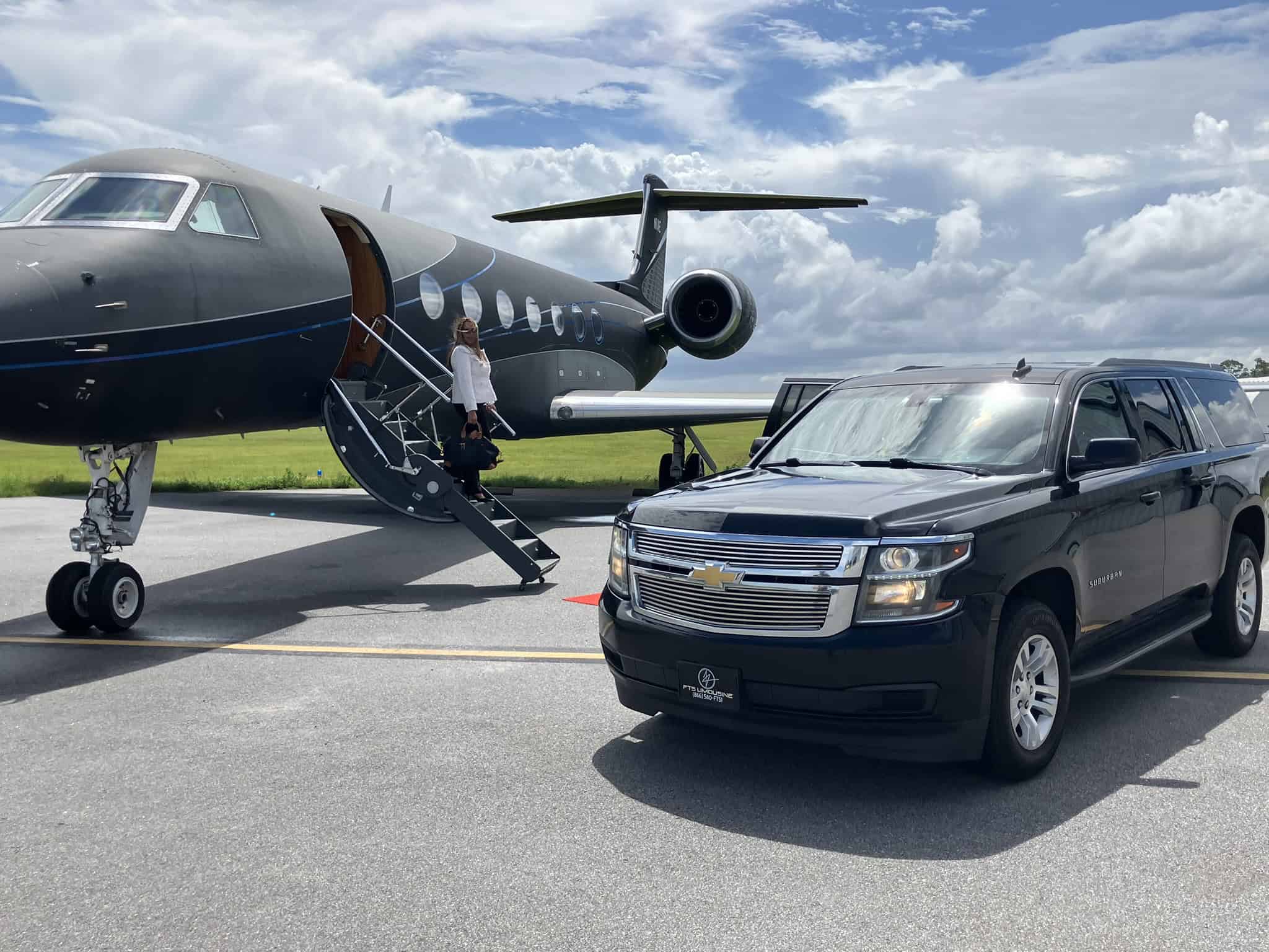 Passenger descending a private aircraft beside a luxury black SUV providing private airport car service and executive transportation.