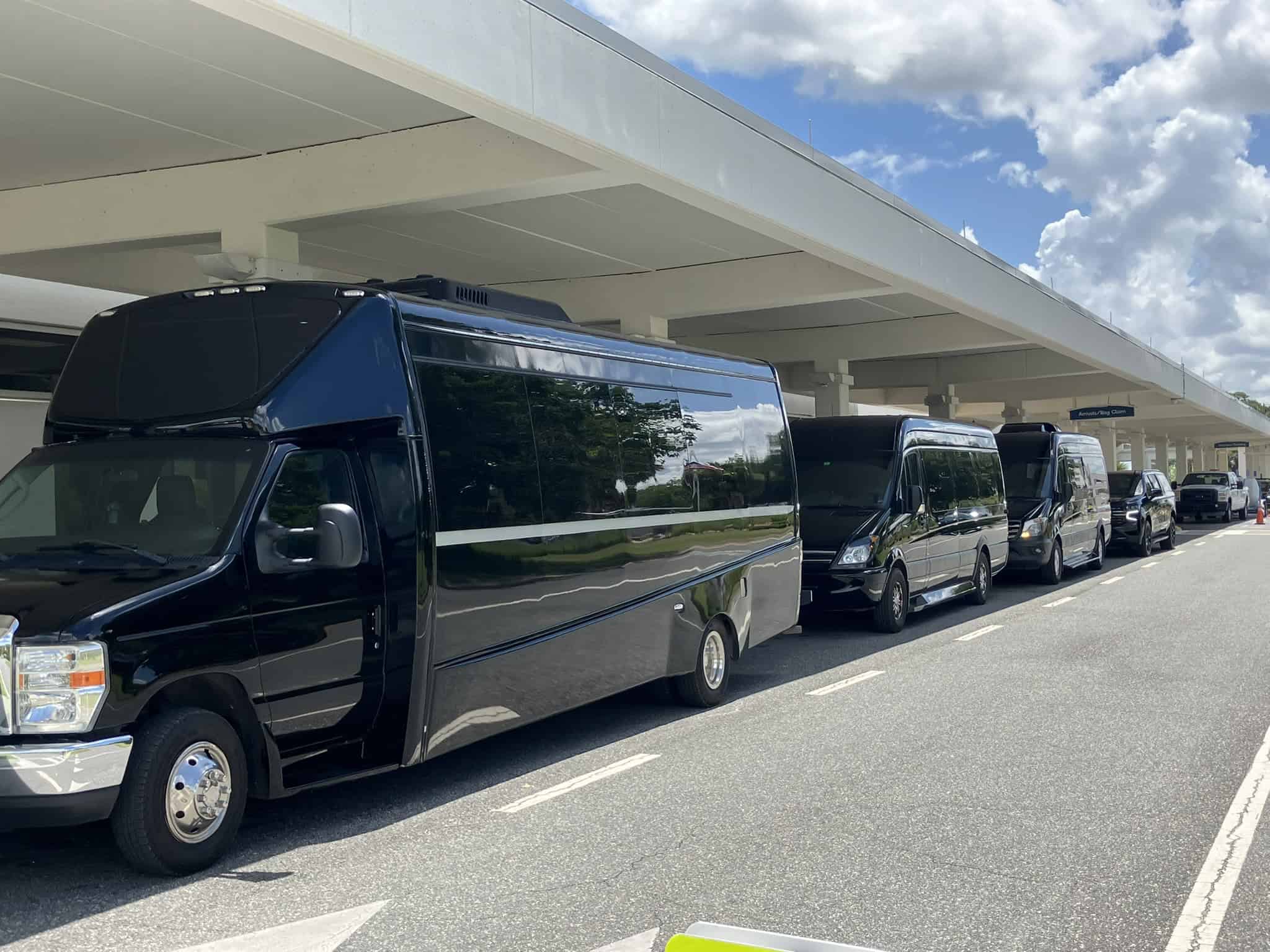 FTS Limousine executive shuttle bus, two Mercedes Sprinters, and a luxury SUV staged outside the arrivals and baggage claim area at Gainesville Regional Airport in Gainesville, Florida.