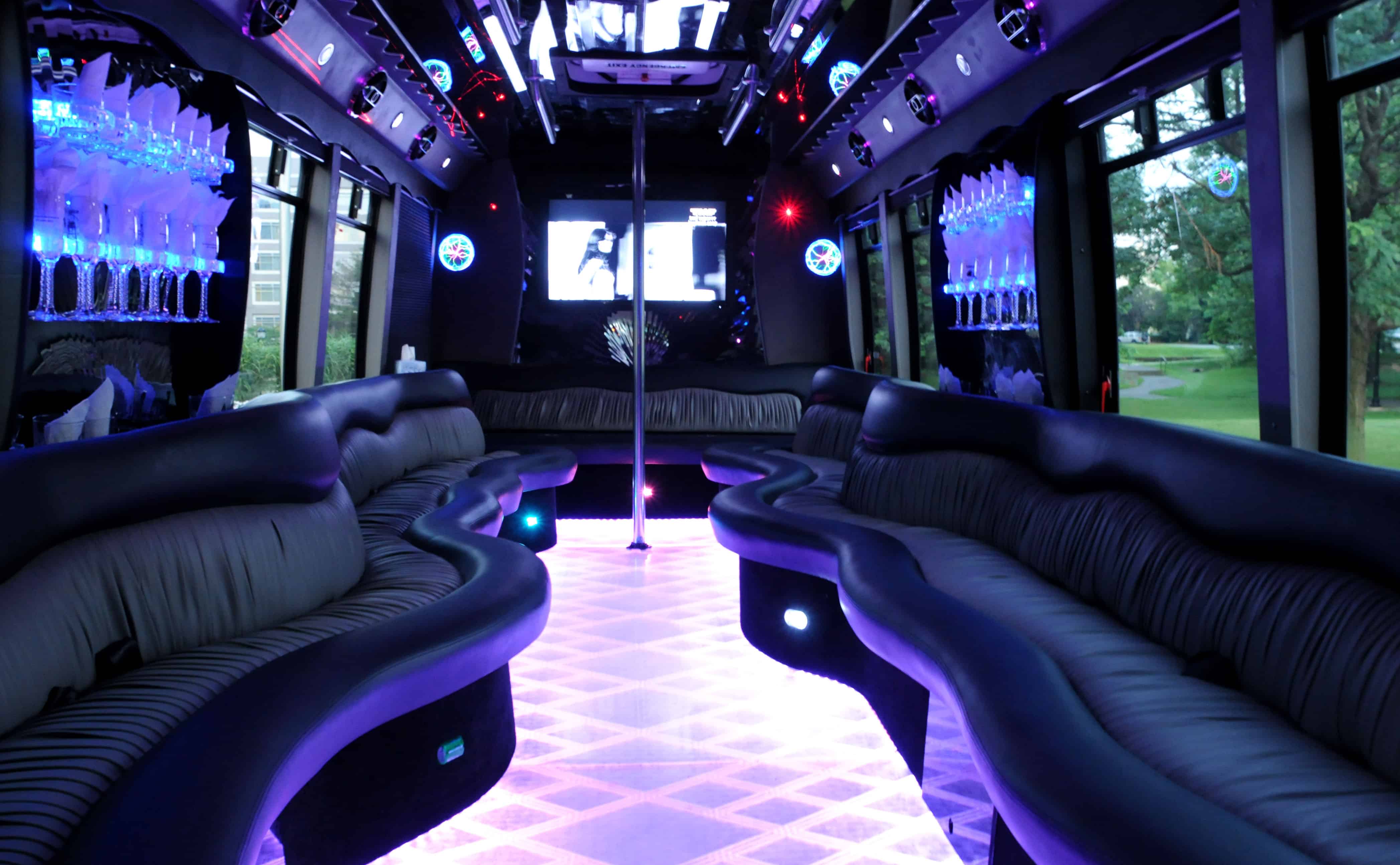 Interior of a luxury limo bus featuring plush leather seating, ambient LED lighting, premium entertainment systems, and spacious passenger accommodations.