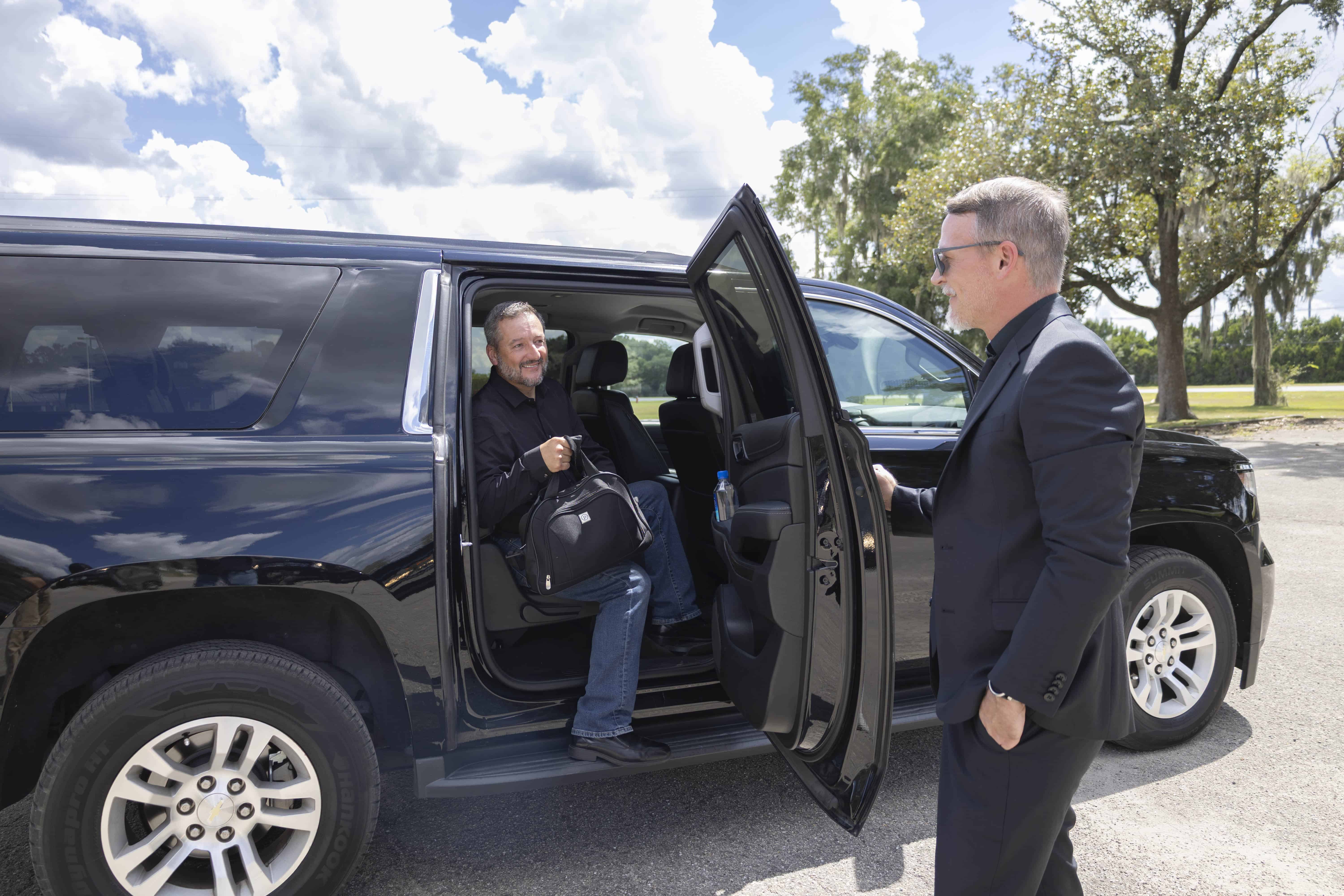 Business traveler exiting a luxury black SUV with assistance from a professional chauffeur at a medical office in Alachua, Florida.