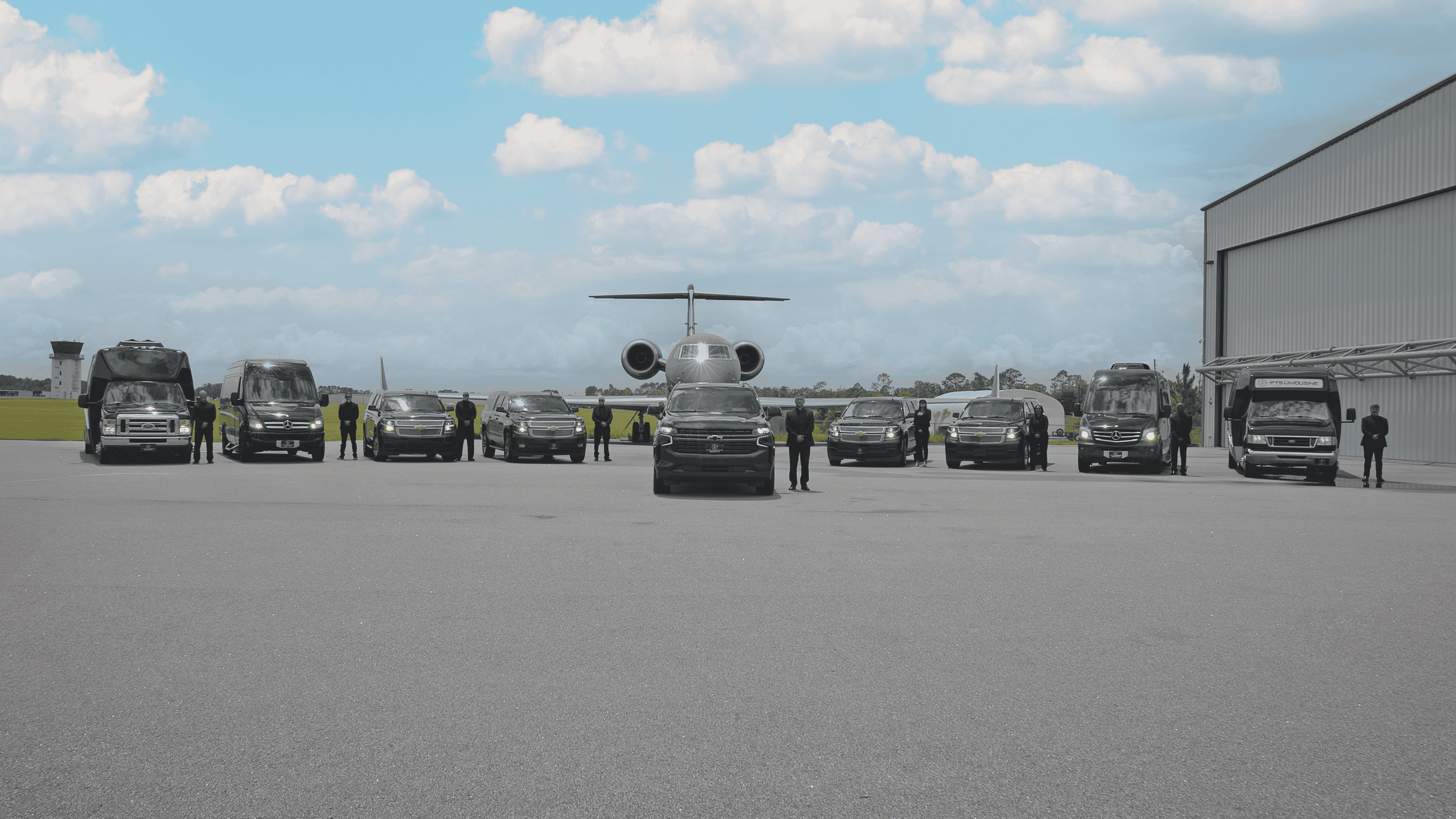 FTS Limousine chauffeurs standing beside executive SUVs, Sprinter vans, and luxury vehicles with a luxury GV jet positioned behind them at University Air Center in Gainesville, providing private airport transportation.
