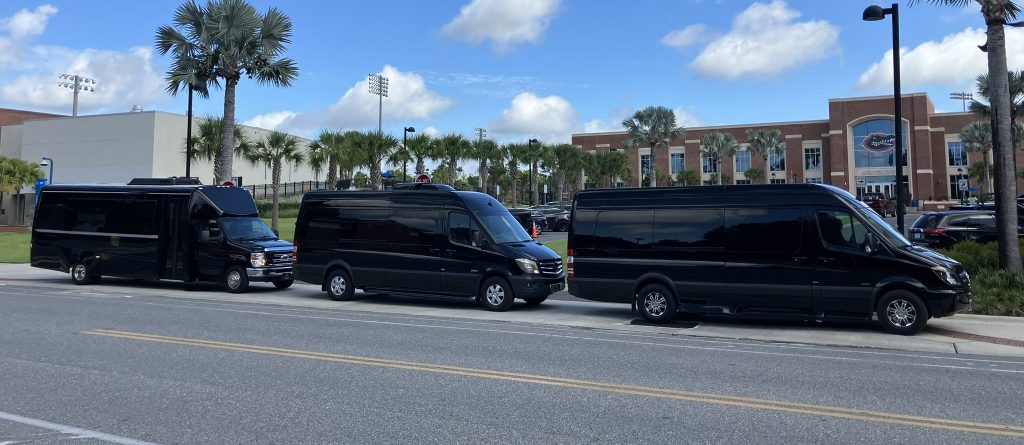 Luxury Mercedes Sprinter vans and executive shuttle bus staged outside the University of Florida Heavener Football Facility in Gainesville, FL for game day group transportation.