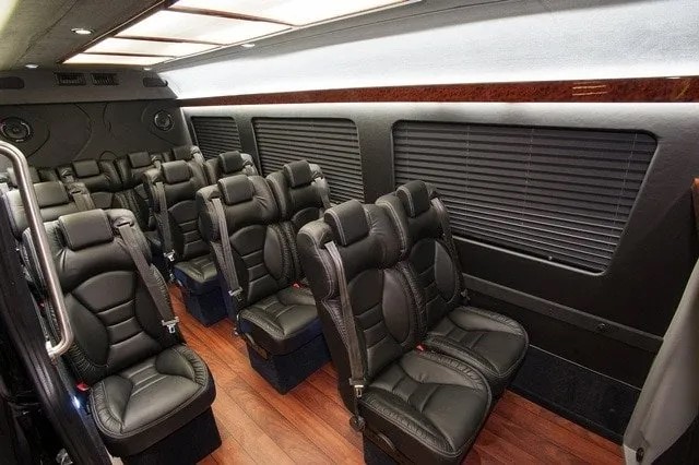Interior of a luxury Mercedes Sprinter with executive captain seats and wood flooring.