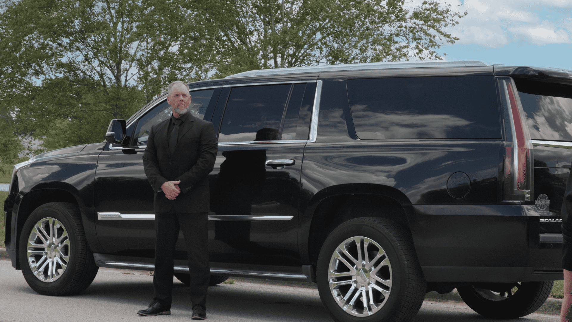 Professional FTS Limousine chauffeur standing beside a Cadillac Escalade SUV ready to welcome arriving passengers.
