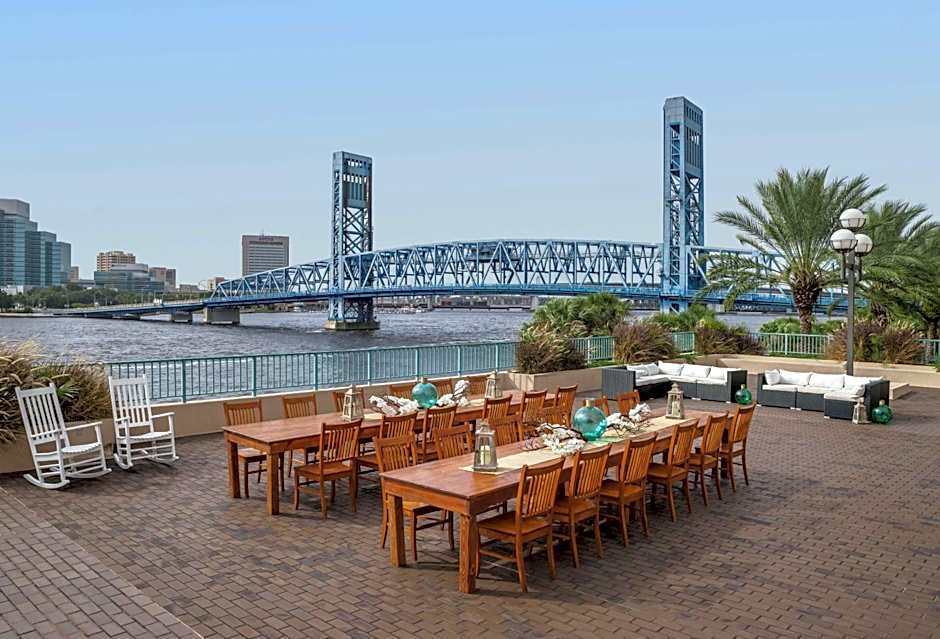 Wedding reception tables and chairs arranged on the outdoor pavilion at Hyatt Regency Jacksonville Riverfront overlooking the St. Johns River and Jacksonville skyline.