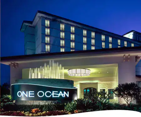 Exterior entrance of One Ocean Resort & Spa in Atlantic Beach, Florida, illuminated at night with the resort's entrance sign and porte-cochère.