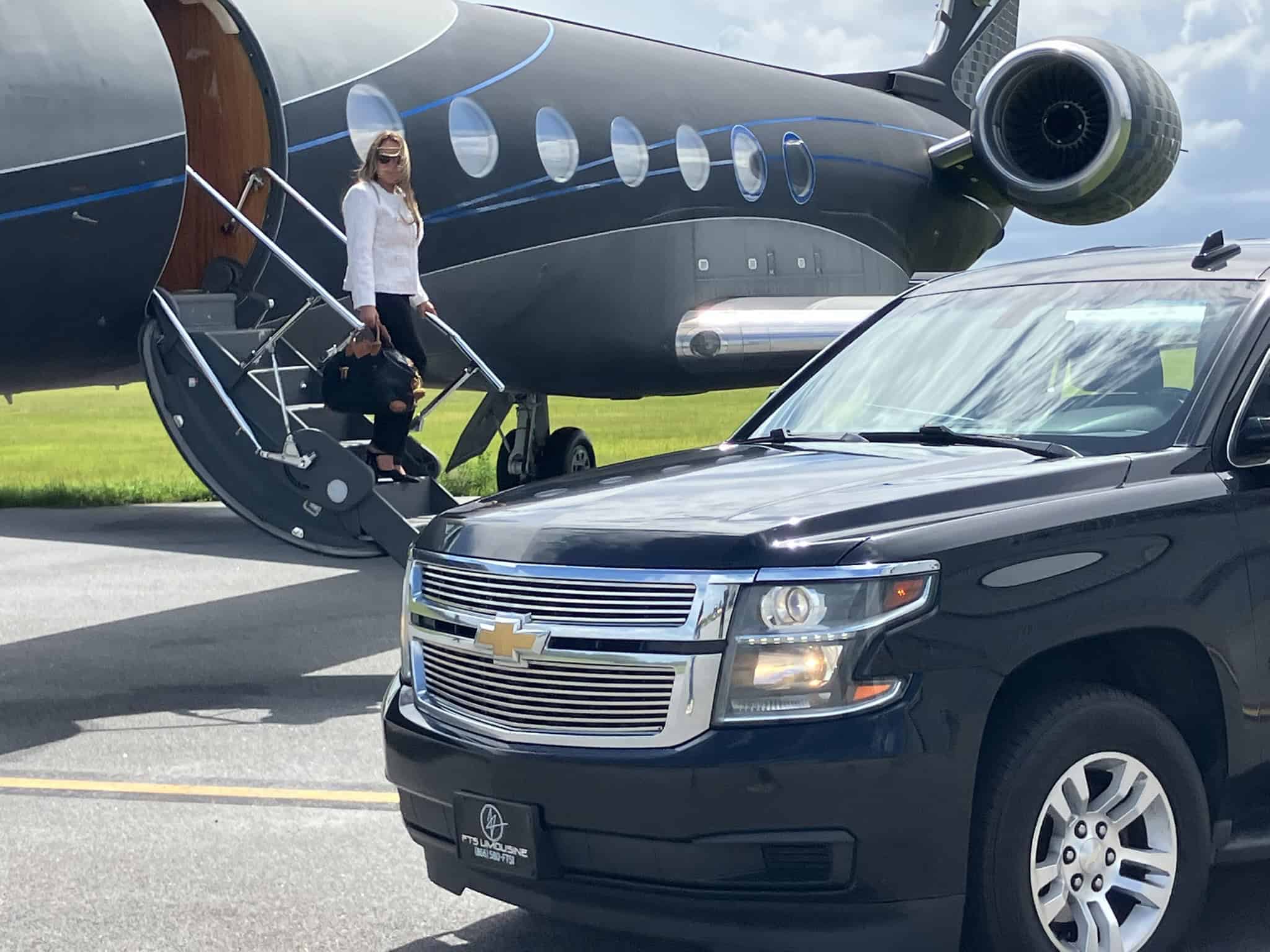 Passenger exiting a Gulfstream G5 private jet as an FTS Limousine luxury SUV awaits planeside on the tarmac.